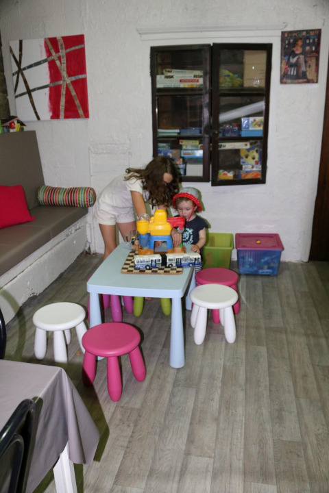Due bambini giocano con i giocattoli a un tavolino in una sala giochi colorata al Camping Moulin de Chaules.