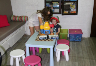 Due bambini giocano con i giocattoli a un tavolino in una sala giochi colorata al Camping Moulin de Chaules.
