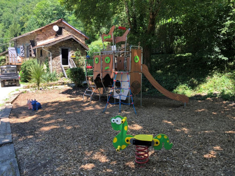 Parco giochi con scivolo e giochi a molla accanto a una casa in pietra presso Moulin de Chaules.