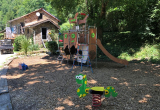 Parco giochi con scivolo e giochi a molla accanto a una casa in pietra presso Moulin de Chaules.