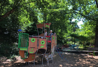 Bambini giocano su una nave pirata nel parco giochi immerso nel verde al campeggio Moulin de Chaules.