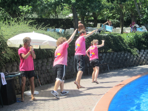 Ferieparkpersonale i lyserøde T-shirts laver sjov ved poolen i Centro Vacanze San Marino i San Marino.