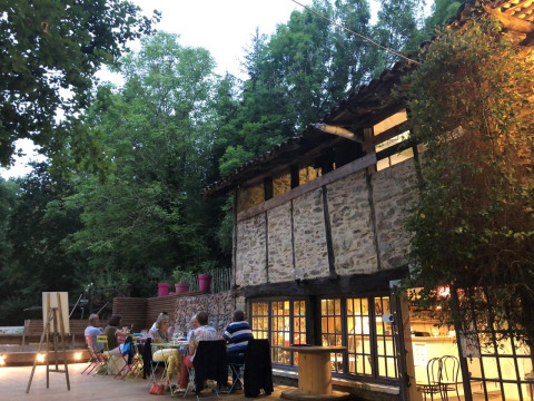 Outdoor dining area at Moulin de Chaules campsite in France, with people enjoying an evening meal by the lodge.