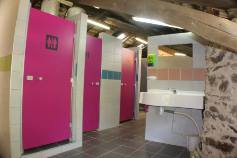 Shared bathroom facilities with pink doors and a sink at Campsite Moulin de Chaules in France.