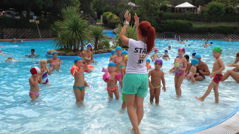Bambini seguono una lezione di nuoto con un'istruttrice nella piscina esterna del Centro Vacanze San Marino.