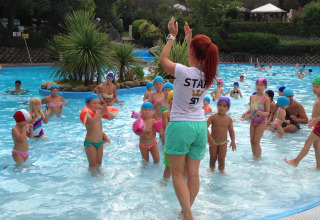 Kinderen volgen een zwemles met een begeleidster in het buitenzwembad van Centro Vacanze San Marino.