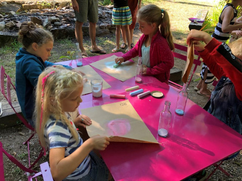Children do art activities outdoors at a pink table at the Moulin de Chaules campsite in France.