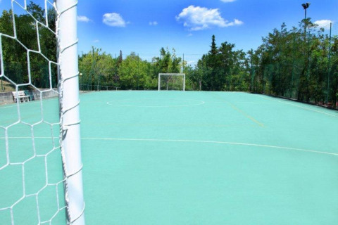 Terrain de football extérieur au Centro Vacanze San Marino, entouré d’arbres et de ciel bleu clair.
