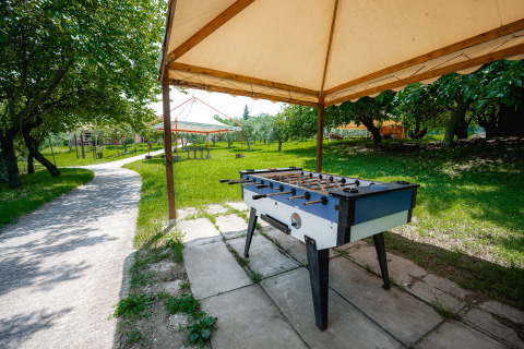 Bordfodbold under et telt ved Centro Vacanze San Marino, med grønne træer og stier i baggrunden.