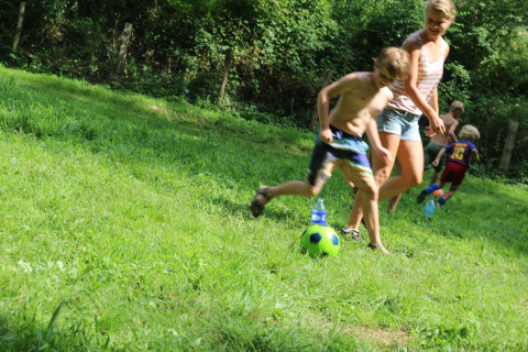 Children and adults play soccer on the grass at Campsite Moulin de Chaules in Auvergne-Rhône-Alpes, France.