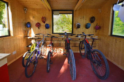 Sala de bicicletas con varios modelos y cascos en las paredes de madera en Centro Vacanze San Marino.
