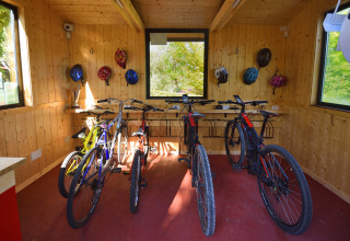 Sala de bicicletas con varios modelos y cascos en las paredes de madera en Centro Vacanze San Marino.