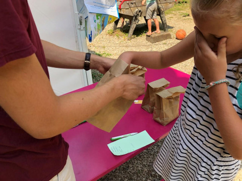 A child joins a sensory guessing game with paper bags at Campsite Moulin de Chaules, Auvergne-Rhône-Alpes.