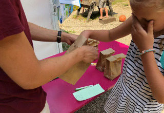 Un bambino partecipa a un gioco sensoriale con sacchetti di carta al campeggio Moulin de Chaules, Alvernia-Rodano-Alpi.