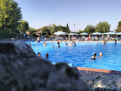 Drukbezocht zwembad bij Centro Vacanze San Marino met zwemmers en ligzetels onder blauwe parasols.