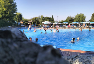 Piscine animée au Centro Vacanze San Marino, avec baigneurs et chaises longues sous des parasols bleus.