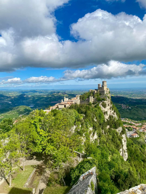 Vue d'une forteresse médiévale au sommet d'une colline rocheuse, entourée de verdure à Saint-Marin, Saint-Marin.