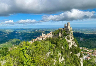 Vue d'une forteresse médiévale au sommet d'une colline rocheuse, entourée de verdure à Saint-Marin, Saint-Marin.