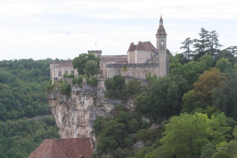 Un castello storico arroccato su una scogliera circondata da boschi vicino a Saint Constant, Auvergne-Rhône-Alpes, Francia.