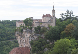 Un castello storico arroccato su una scogliera circondata da boschi vicino a Saint Constant, Auvergne-Rhône-Alpes, Francia.