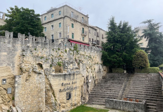 Oud stenen amfitheater en stadsmuren in San Marino, omringd door bomen en residentiële gebouwen.