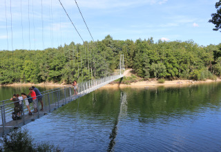 Persone attraversano un ponte sospeso su un fiume vicino a Saint Constant, Auvergne-Rhône-Alpes, Francia.