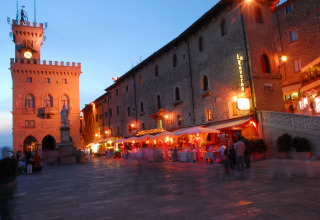 Vista nocturna de una animada plaza con edificios históricos y restaurantes en Repubblica di San Marino, San Marino.