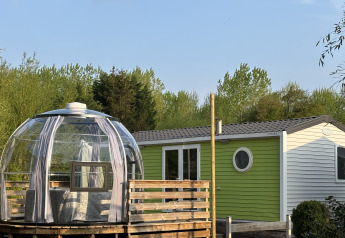 Bungalow Le Grand Marais with jacuzzi, modern glass dome and green cabin surrounded by lush greenery.