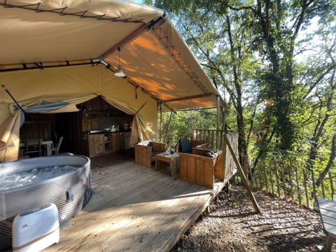 Safari Lodge Spa: Spacious tent deck with hot tub, cozy seating, and a scenic wooded view for relaxation.