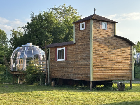 Klein houten huis Château Mobile met een dompel-jacuzzi buiten, gelegen op een groene grasveld.