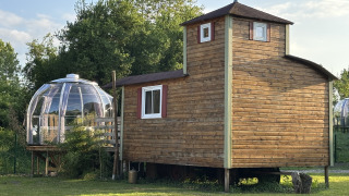 Klein houten huis Château Mobile met een dompel-jacuzzi buiten, gelegen op een groene grasveld.