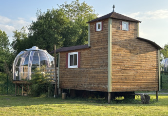 Tiny house en bois Château Mobile avec un jacuzzi bulle extérieur, installée sur une pelouse verte.