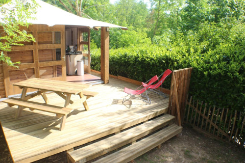 Houten terras met picknicktafel, twee rode ligstoelen en lodge op Moulin de Chaules camping, Frankrijk.