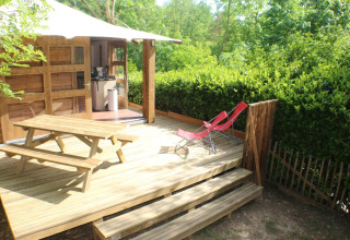 Outdoor deck with picnic table, two red lounge chairs and a lodge at Lodge «Bali», Moulin de Chaules campsite.