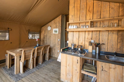 Indretningen af et glamping telt, Centro Vacanze San Marino - Safaritenten San Marino, træmøbler og køkken.