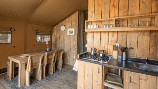 Interno della tenda glamping Centro Vacanze San Marino - Safaritenten San Marino con cucina e arredi in legno.