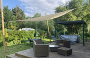 Buitenterras met rotanmeubels, schaduwdoek en jacuzzi bij Luxe Lodge, Flower Camping de la Trye in Frankrijk.