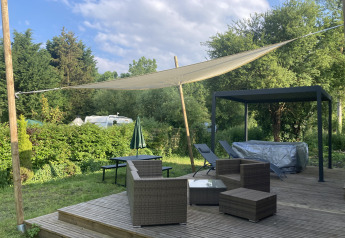 Terrasse extérieure avec meubles en osier, voile d'ombrage et jacuzzi au Luxe Lodge, Flower Camping de la Trye.