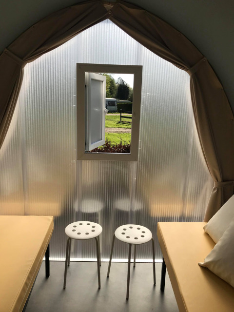 Binnenkant van een safaritent 'Cocosweet' op Flower Camping de la Trye in Frankrijk, met twee bedden, krukken en een raam.