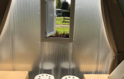 Binnenkant van een safaritent 'Cocosweet' op Flower Camping de la Trye in Frankrijk, met twee bedden, krukken en een raam.