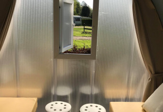Binnenkant van een safaritent 'Cocosweet' op Flower Camping de la Trye in Frankrijk, met twee bedden, krukken en een raam.
