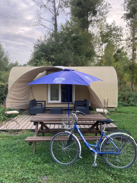 Safaritent Cocosweet bij Flower Camping de la Trye in Frankrijk met fiets, bank en blauwe parasol ervoor.