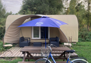Safaritent Cocosweet bij Flower Camping de la Trye in Frankrijk met fiets, bank en blauwe parasol ervoor.