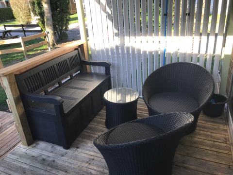 Outdoor seating area at Green Chalet, Flower Camping de la Trye in France with chairs and bench.