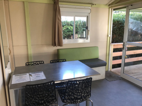 Comedor interior en el Green Chalet de Flower Camping de la Trye, Francia, con mesa y sillas modernas.