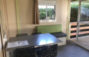 Zona pranzo interna con tavolo e sedie moderne al Green Chalet di Flower Camping de la Trye, Francia.