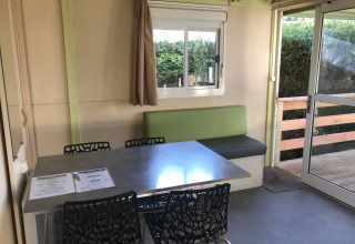 Comedor interior en el Green Chalet de Flower Camping de la Trye, Francia, con mesa y sillas modernas.