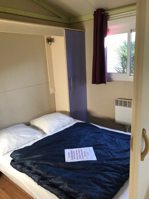 Dormitorio del Green Chalet en Flower Camping de la Trye, Francia, con cama, armario y ventana.