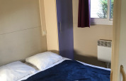 Chambre du Green Chalet au Flower Camping de la Trye en France, avec lit, armoire et fenêtre.