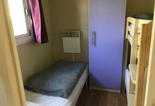 Et lille værelse i Green Chalet med en enkeltseng, køjeseng og garderobe på Flower Camping de la Trye.